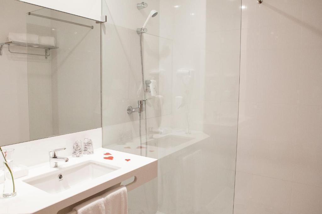 A modern bathroom with a glass-enclosed shower, a white sink, and a mirror.