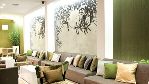 A modern hotel lobby with a long sofa, multiple chairs, and a coffee table. - Flag Hotel Aljustrel (Aljustrel)