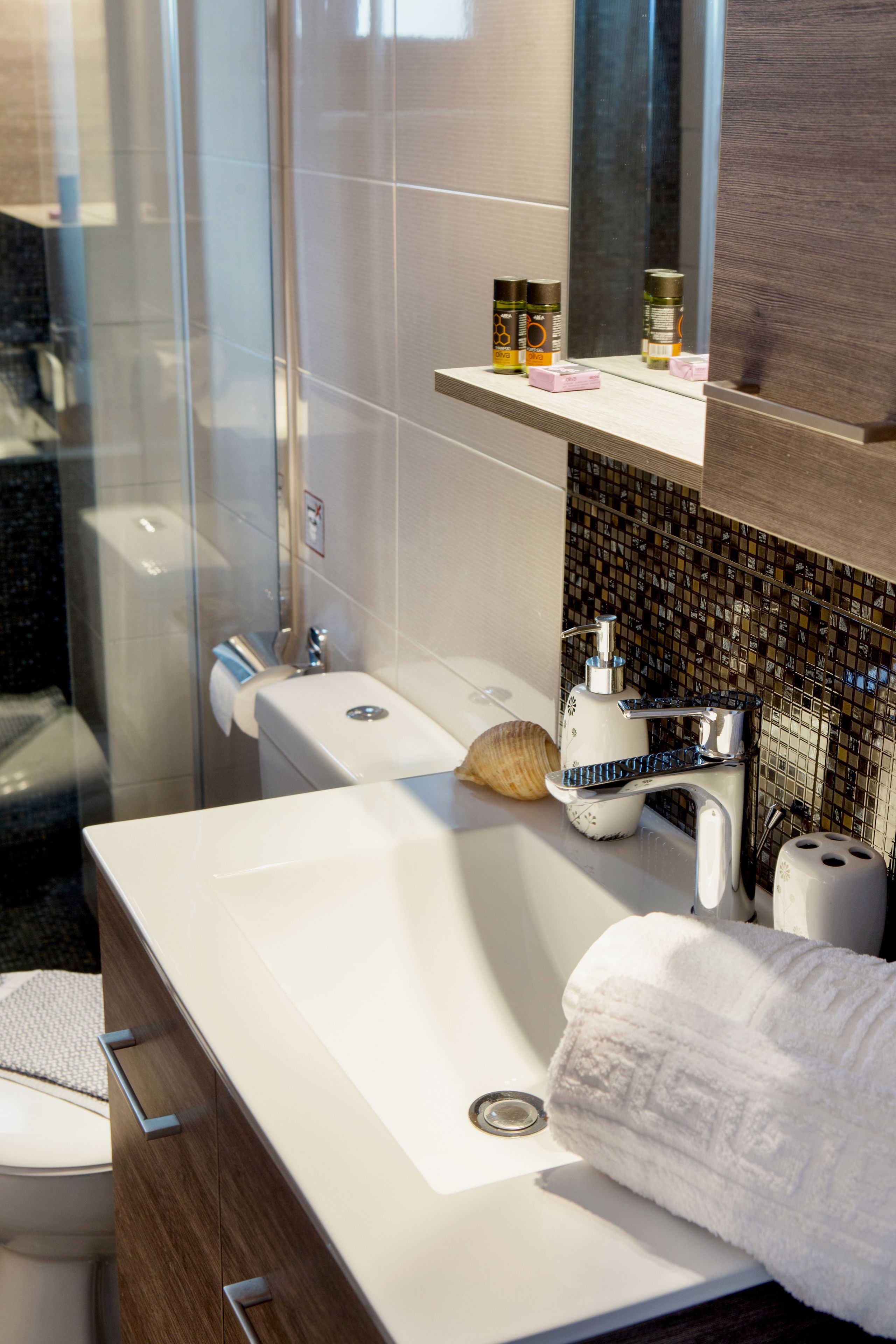 A modern bathroom with a white sink, a glass shower enclosure, and a mirror above the sink.