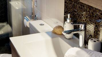 A modern bathroom with a white sink, a glass shower enclosure, and a mirror above the sink.