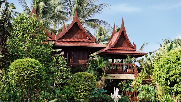 A traditional wooden structure with a peaked roof, surrounded by lush greenery and palm trees. - Ban Keaw Villas (Koh Samui)