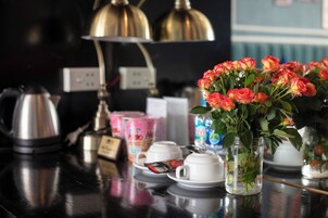 A kitchen counter with a coffee maker, tea set, and a vase of flowers.