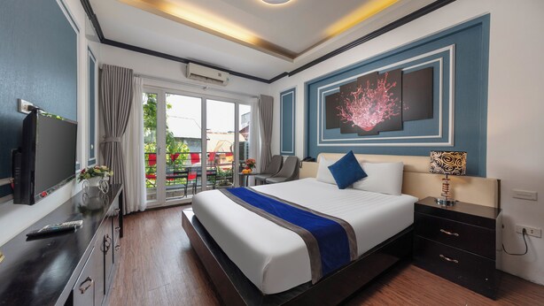 Ein modernes Hotelzimmer mit einem großen Bett, einem Fernseher, einem Schreibtisch und einem Balkon mit Blick.