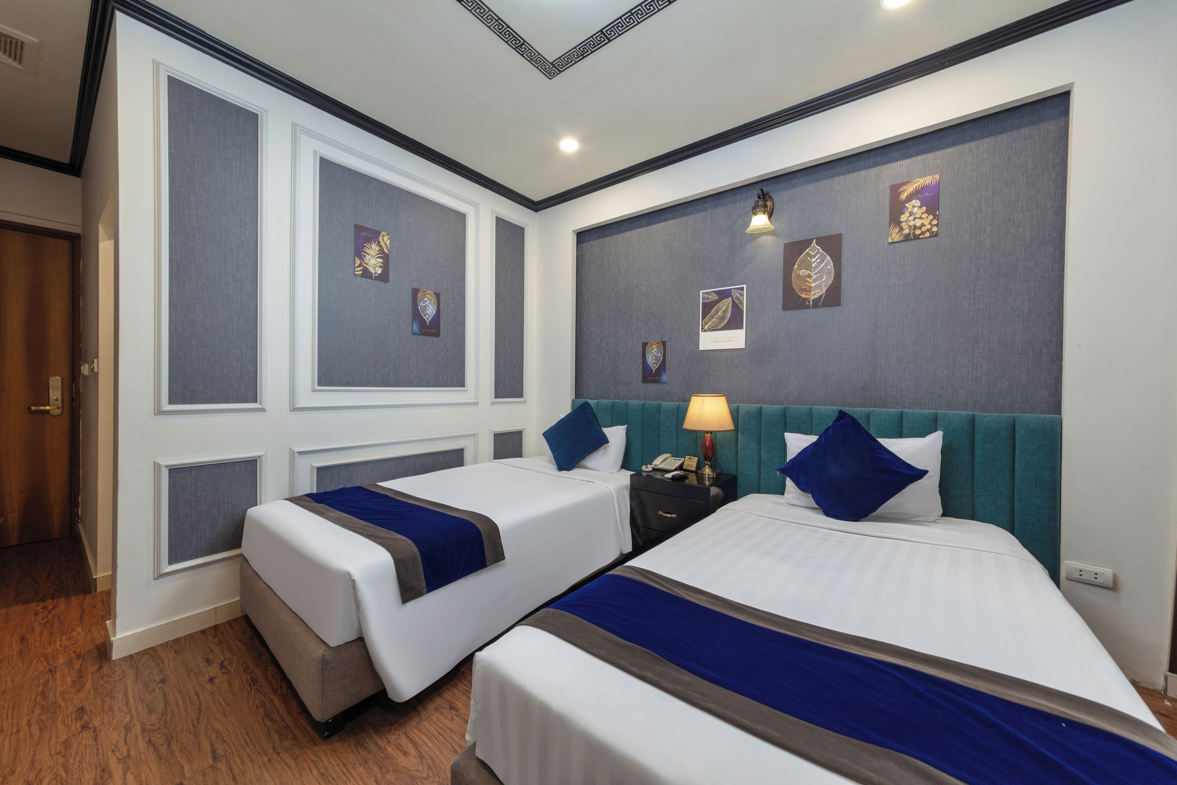 Una habitación de hotel con dos camas, una mesita de noche y una pared decorada con cuadros.