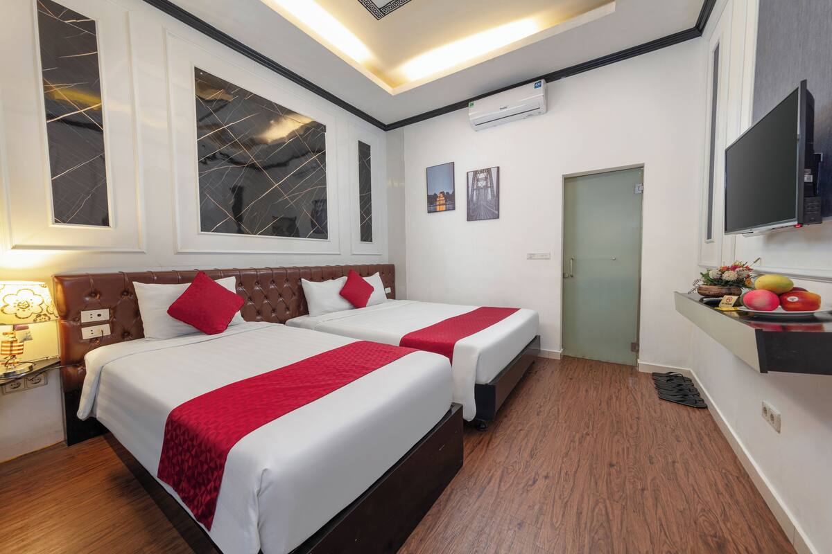 Habitación de hotel con dos camas, televisión y una kitchenette.