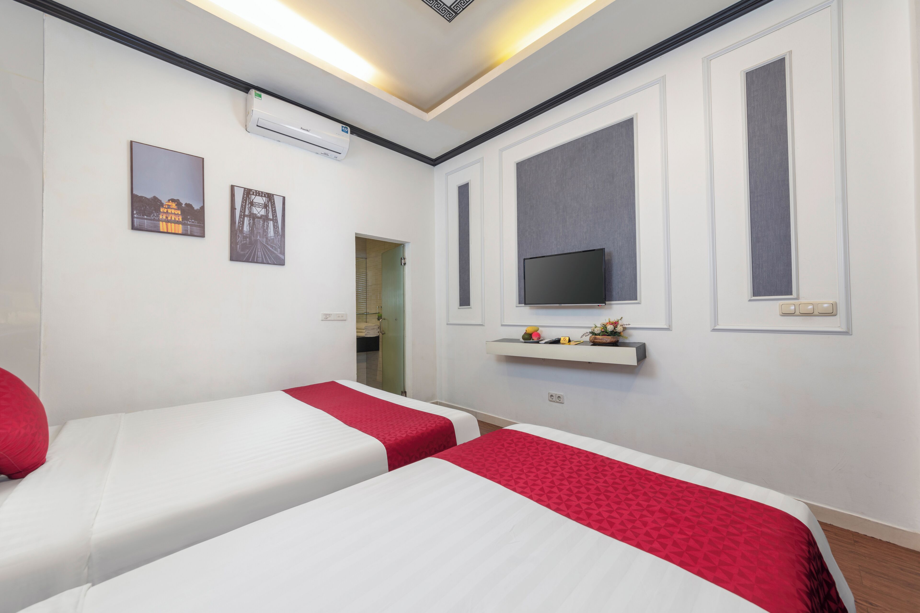 A hotel room with two beds, a TV, and artwork on the walls.