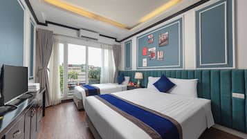 A hotel room with two beds, a television, a desk, and a window with curtains.
