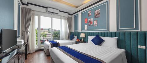 Habitación de hotel con dos camas, televisión, escritorio y ventana con cortinas.