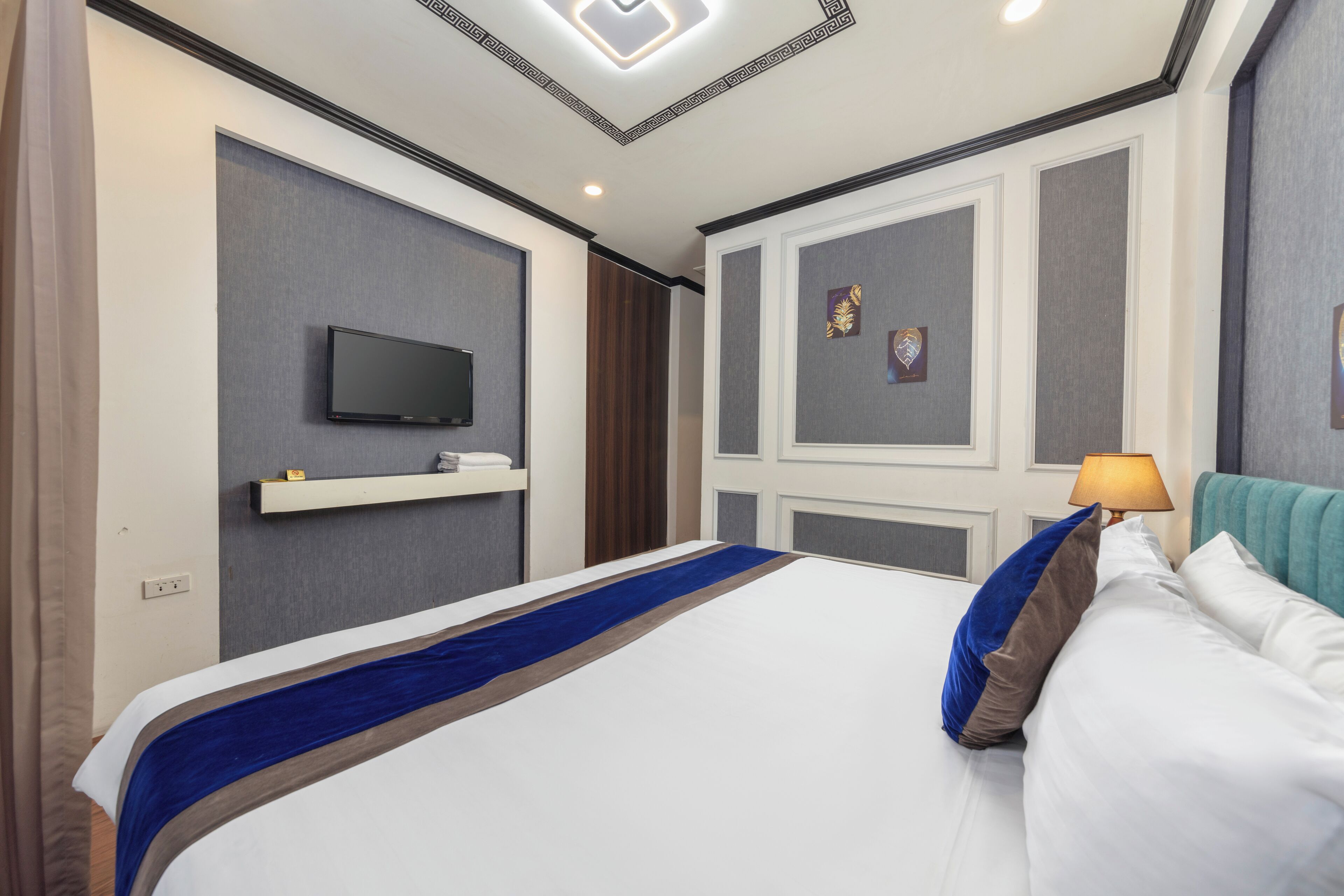 Camera d'albergo con un grande letto, una TV a schermo piatto montata a parete, un comodino e una lampada.