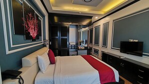 Ein modernes Hotelzimmer mit einem großen Bett, einem Fernseher, einem Schreibtisch und einem durch eine offene Tür einsehbaren Badezimmer.