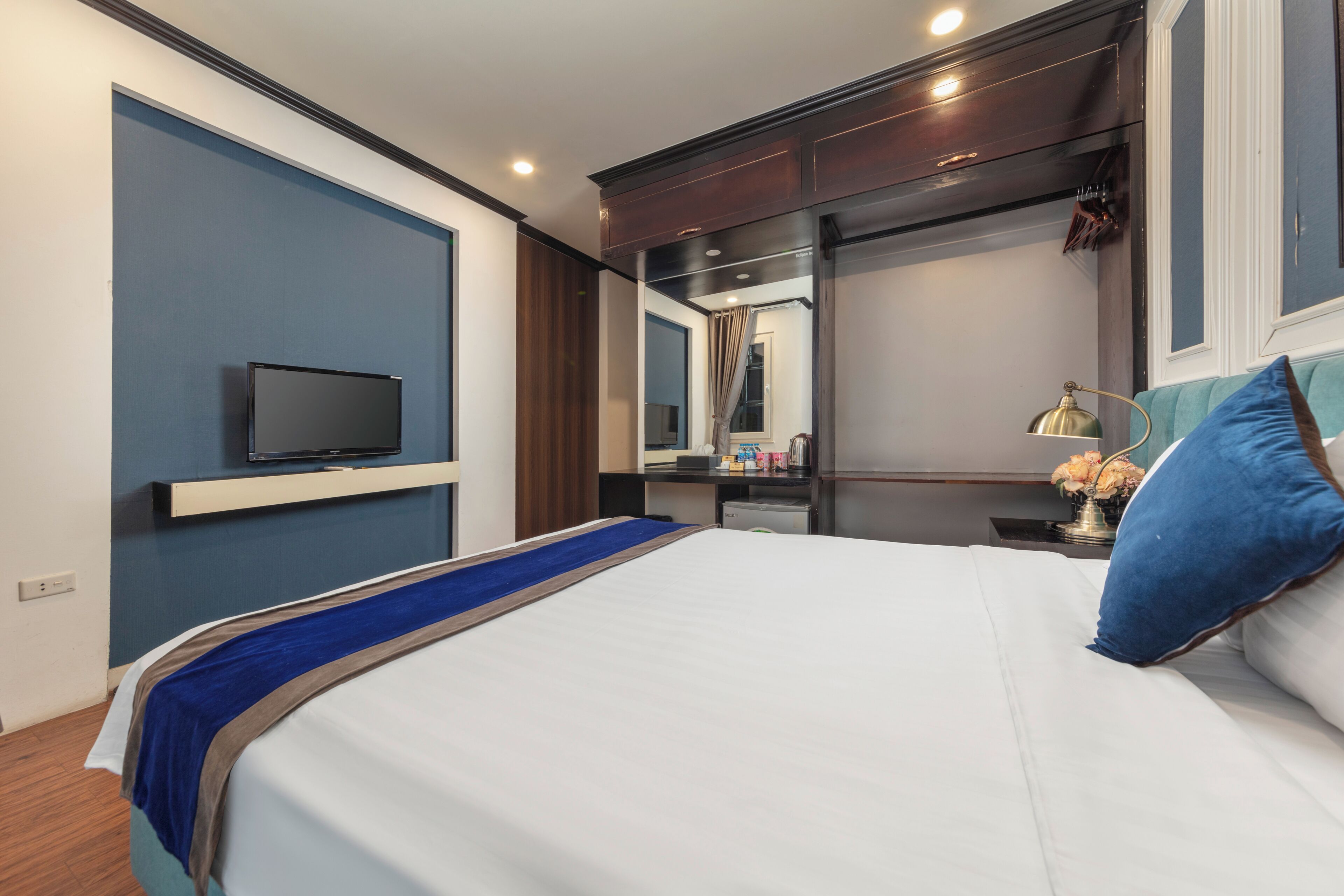 Une chambre d’hôtel équipée d’un lit, d’une télévision, d’un bureau avec une lampe et d’un miroir.