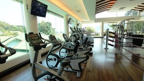 Una palestra con tapis roulant, macchinari per pesi e uno schermo televisivo.