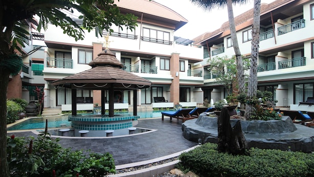 Un cortile con piscina, poltrone relax e un gazebo.