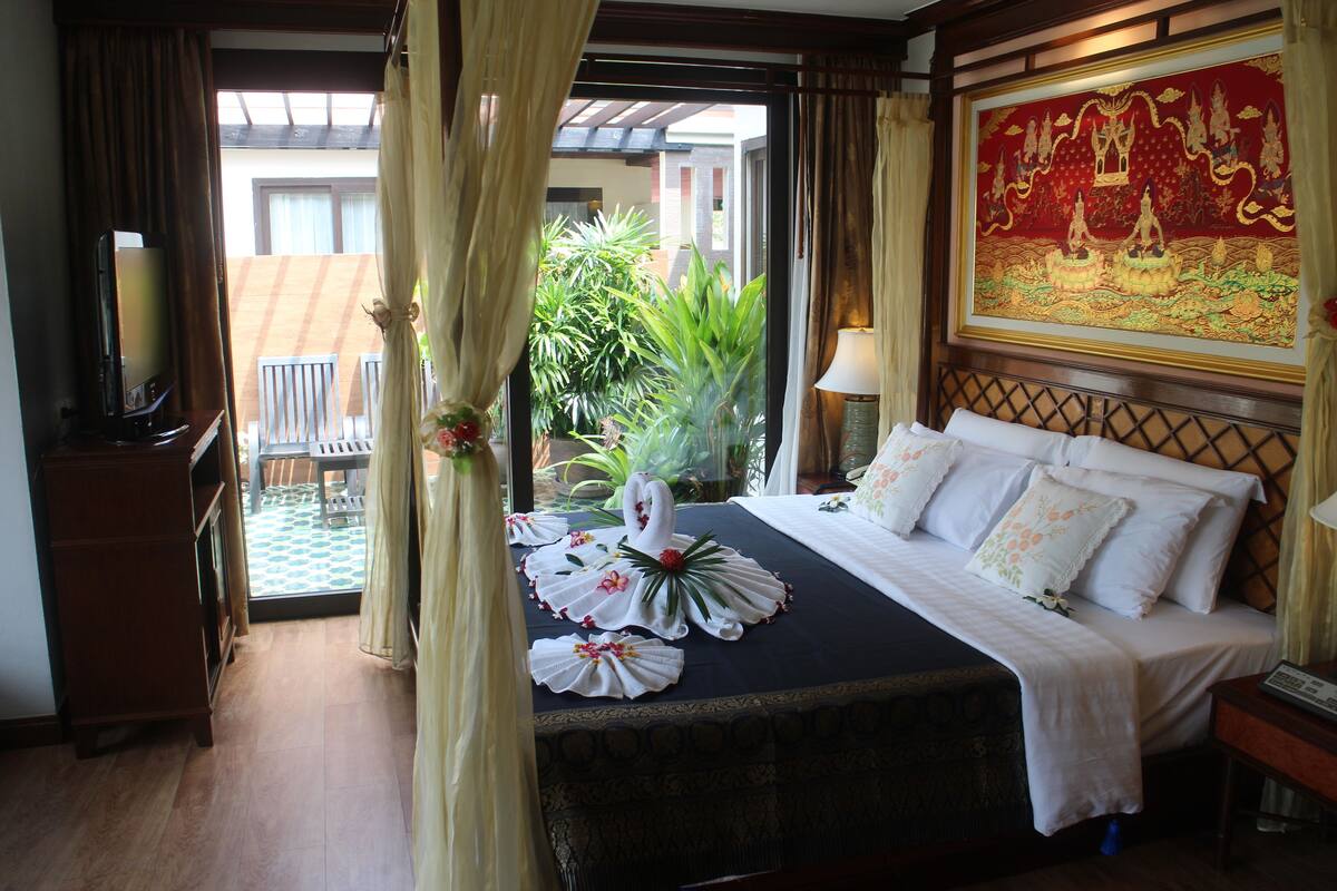 A hotel room with a bed, a TV, a desk, and a view of the outside.