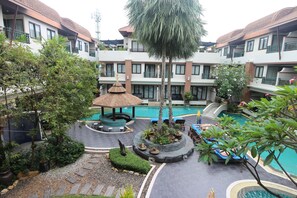 A hotel courtyard with a swimming pool, lounge chairs, and a gazebo.