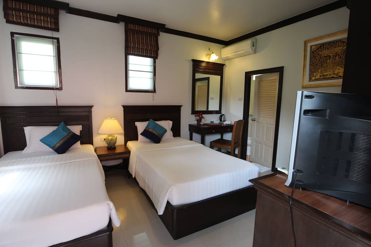 A hotel room with two single beds, a desk with a chair, a television, and a large mirror.