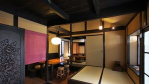 Una habitación tradicional japonesa con suelo de tatami, una mesa de madera baja y una lámpara colgante.