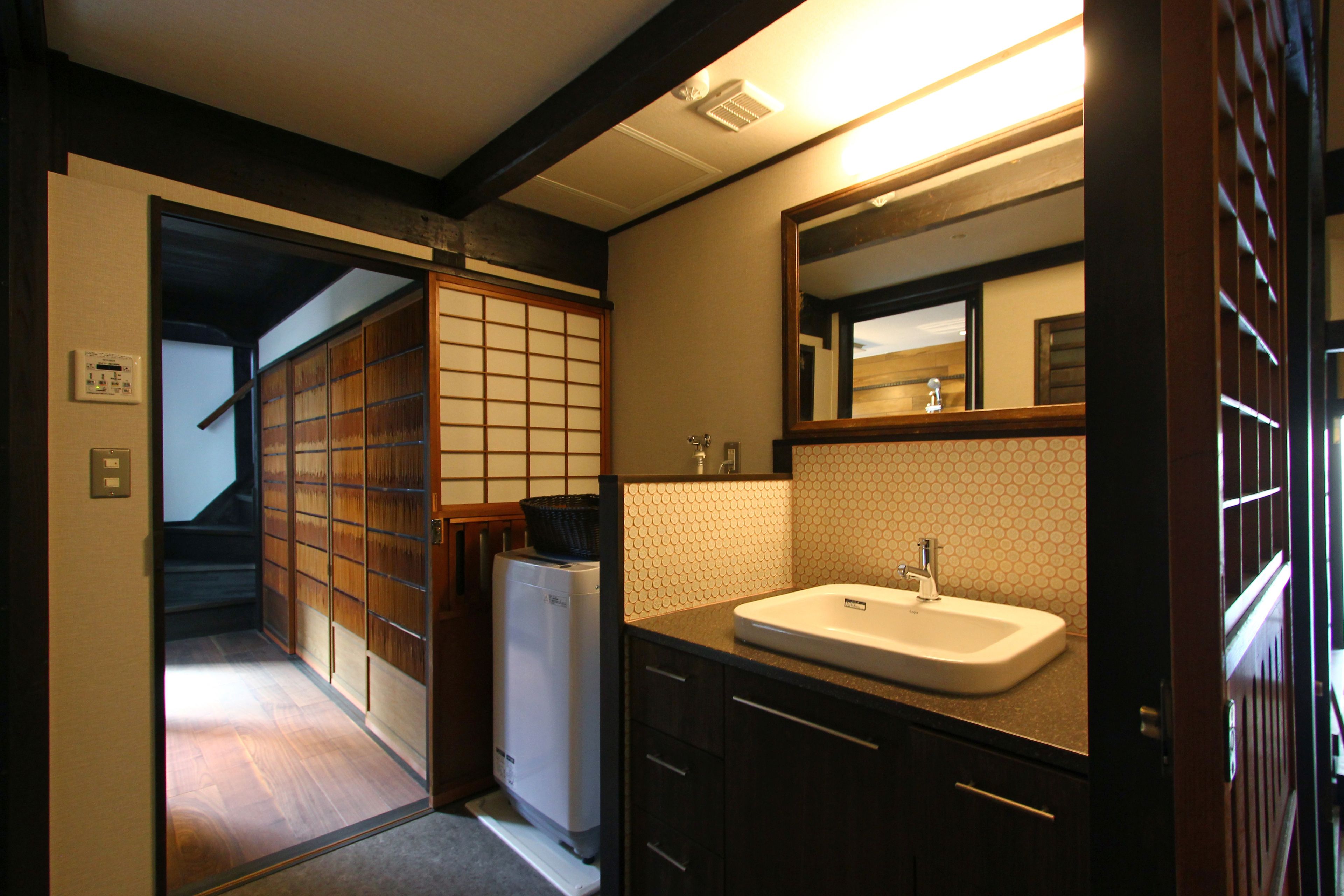 A traditional Japanese-style bathroom with a sink, mirror, and sliding doors.