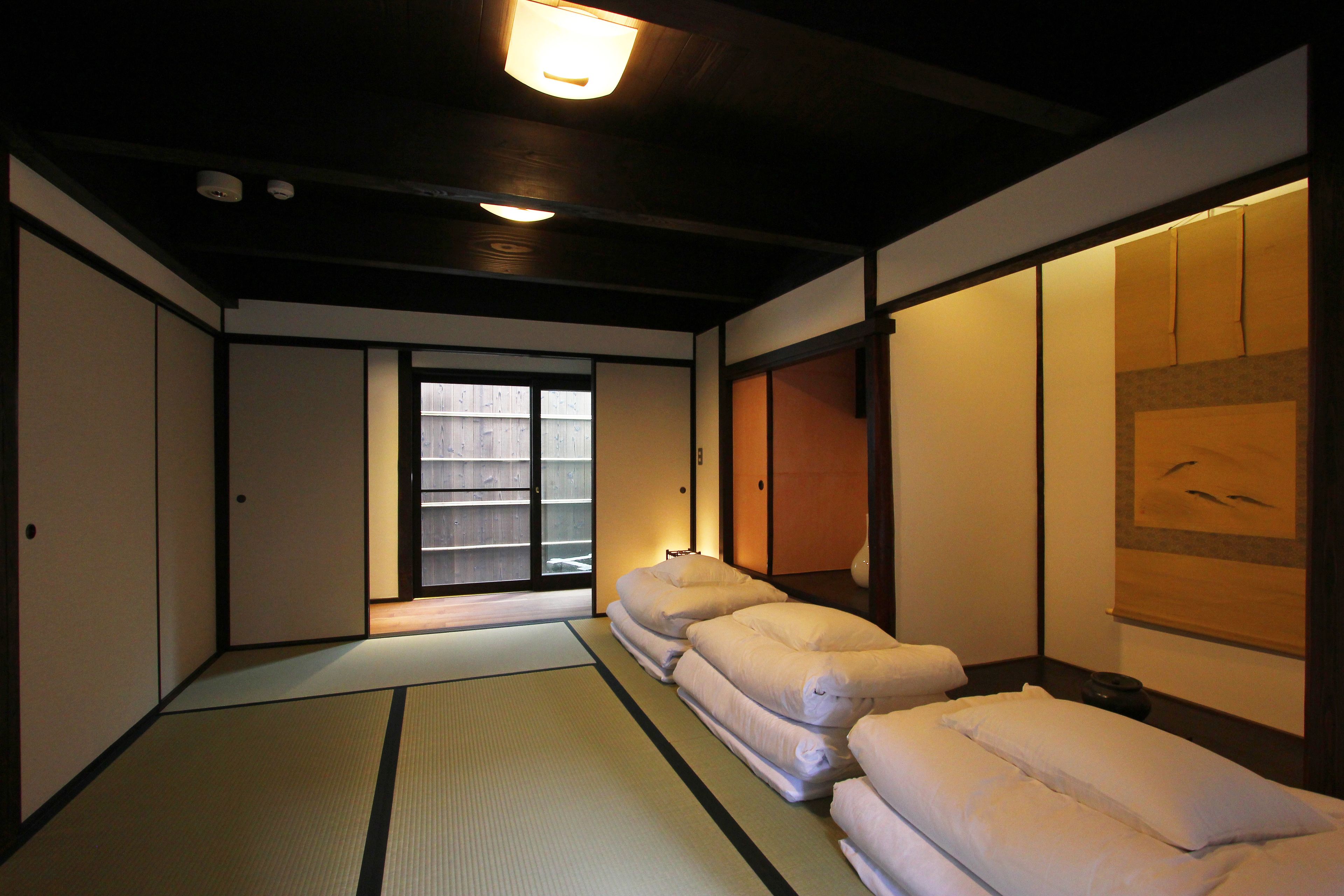 Ett traditionellt japanskt rum med tatamimattor på golvet, skjutdörrar och utsikt över en träveranda.