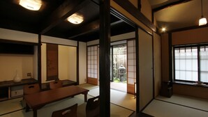 Una habitación japonesa tradicional con suelo de tatami, puertas correderas y una mesa de madera baja con sillas.