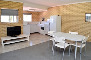 A kitchen with white cabinets, a refrigerator, and a dining table with chairs.