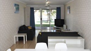 Ein Wohnzimmer mit einer schwarzen Couch, einem weißen Couchtisch und einer TV-Konsole.