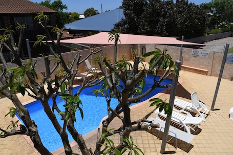 Una piscina al aire libre, sillones reclinables de piscina