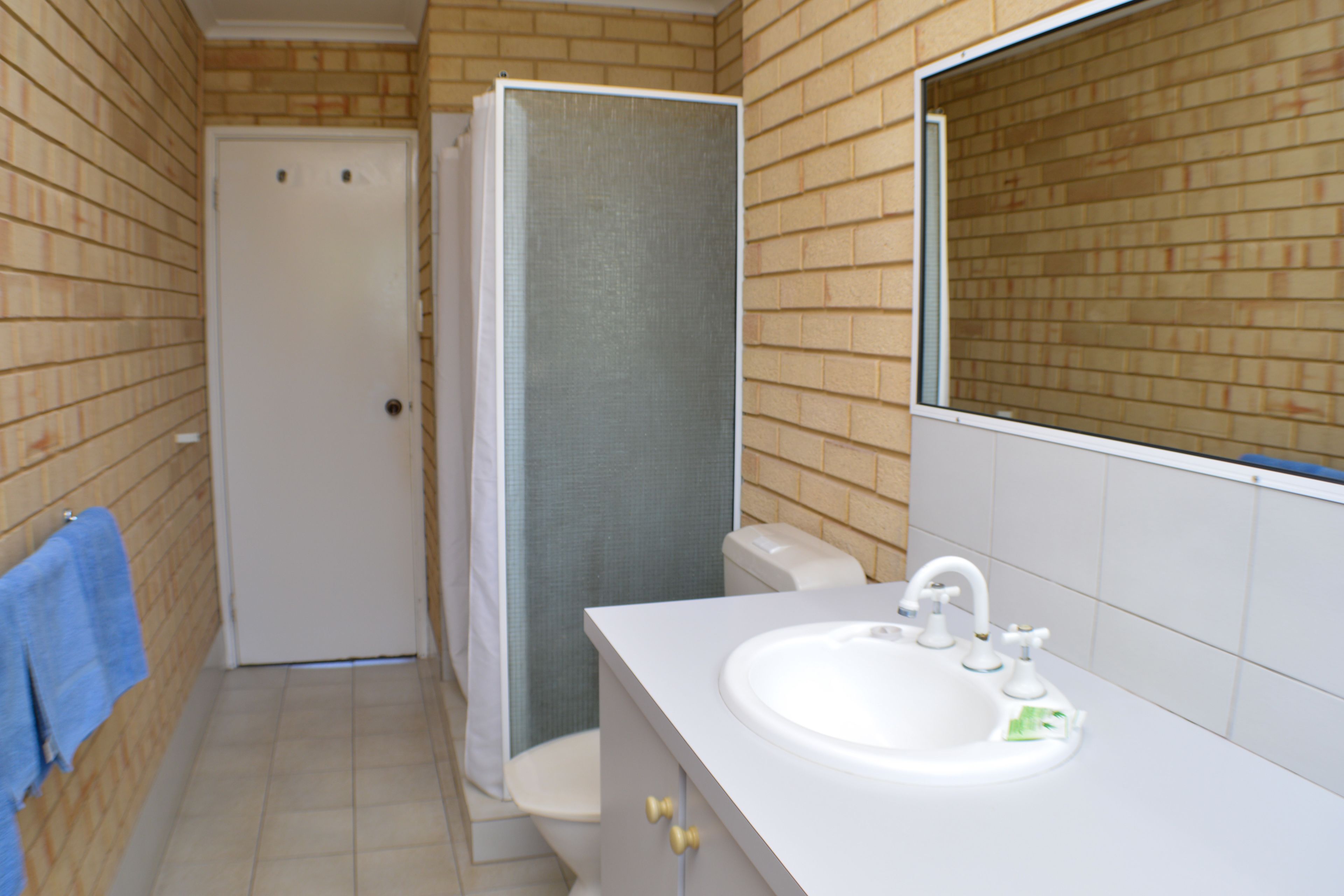 Une salle de bain avec un lavabo blanc, des toilettes et une cabine de douche.