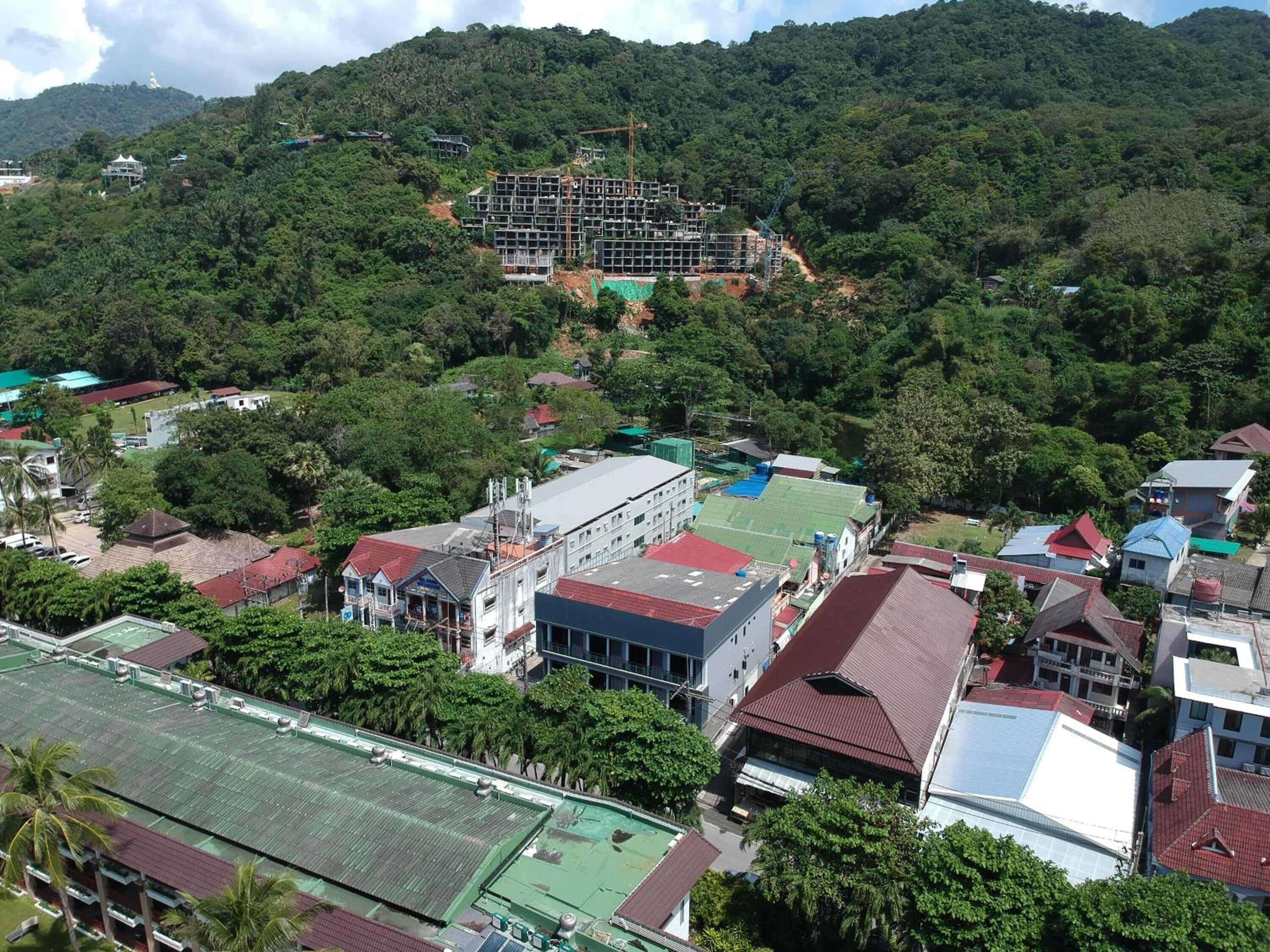 A residential area with various buildings, including a large house under construction and several smaller houses with red roofs.