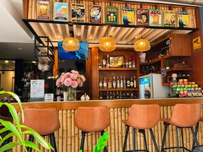 A bar area with wooden shelves, a TV, and a flower vase. - The Mantra Hotel (Karon)