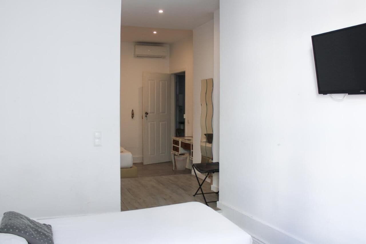 Une chambre d’hôtel avec un lit, un bureau, une chaise et un téléviseur fixé au mur.