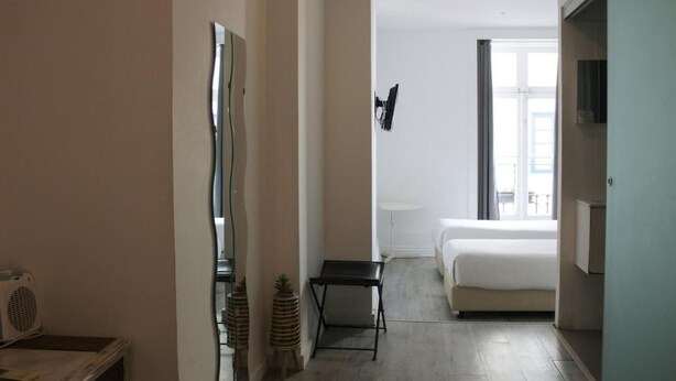 A hotel room with a bed, a small table, a mirror, and a window. - Urban City (Aveiro)