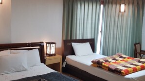Una camera d'albergo con due letti, un comodino con una lampada e una sedia.