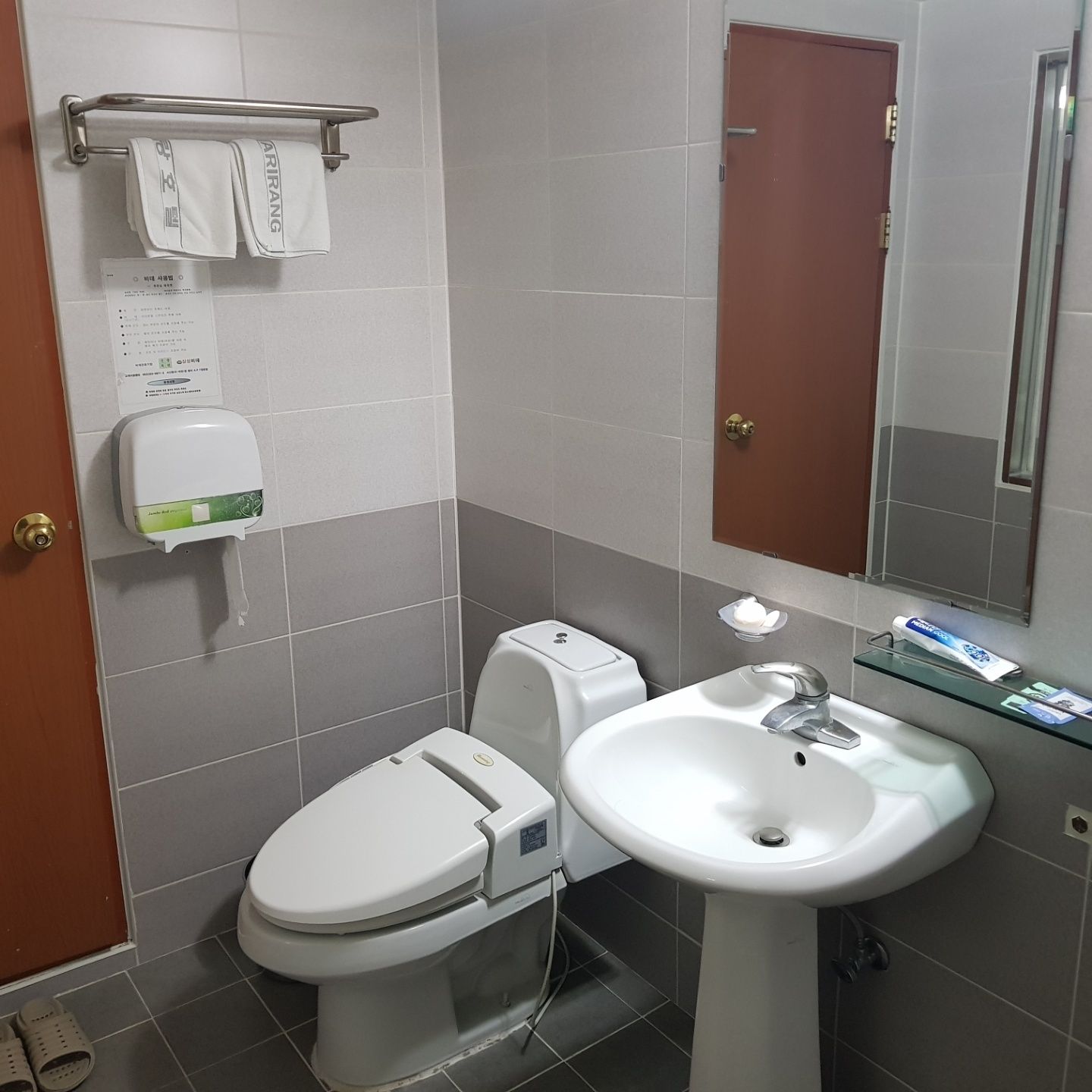 Un baño con inodoro, lavamanos y secamanos.