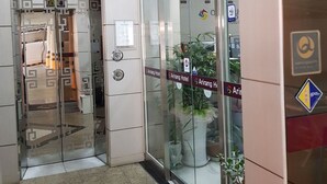 Ingresso di un hotel con porta in vetro, un orologio e insegna dell'Hotel Arirang.