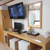 Habitación de hotel con televisión, escritorio con computadora, espejo y cama.