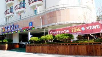 A hotel with a parking sign, a signboard for a restaurant, and a building with balconies.