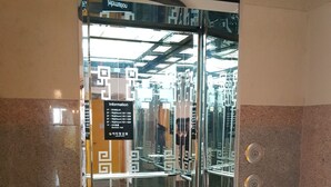 Ingresso di un hotel con porta in vetro, insegna con i numeri delle camere e sala conferenze, e cartello direzionale sopra la porta.