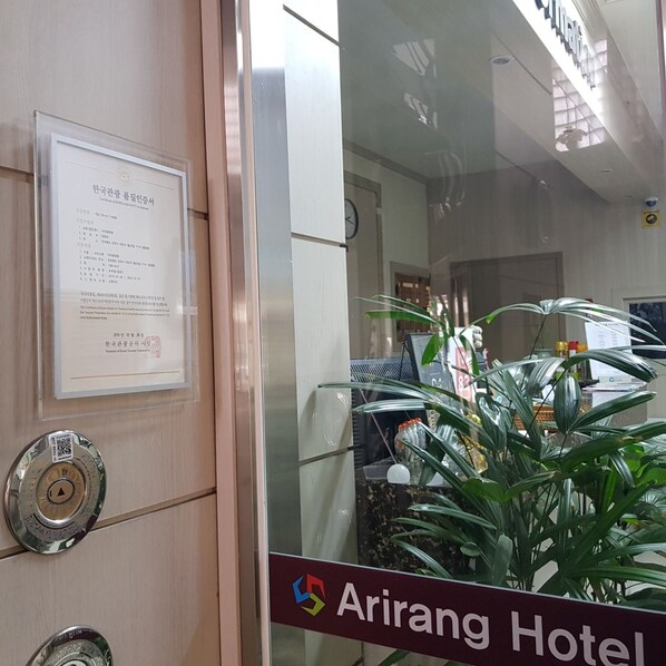 A reception area with a certificate of quality on the wall, a reception desk, and a sign for Arirang Hotel.