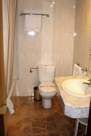 A bathroom with a toilet, sink, and shower curtain.
