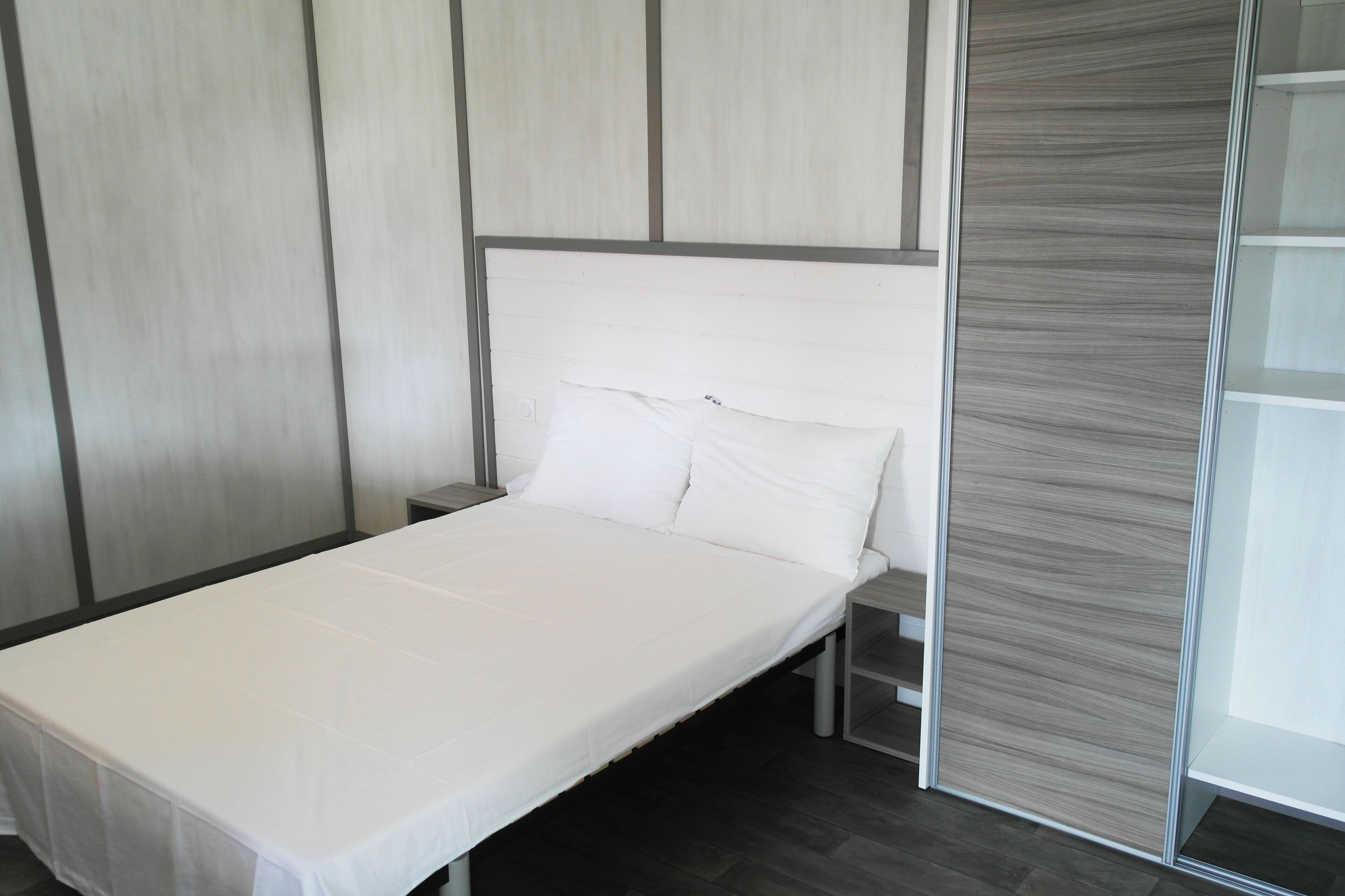 A modern bedroom with a bed, a nightstand, and a sliding door.
