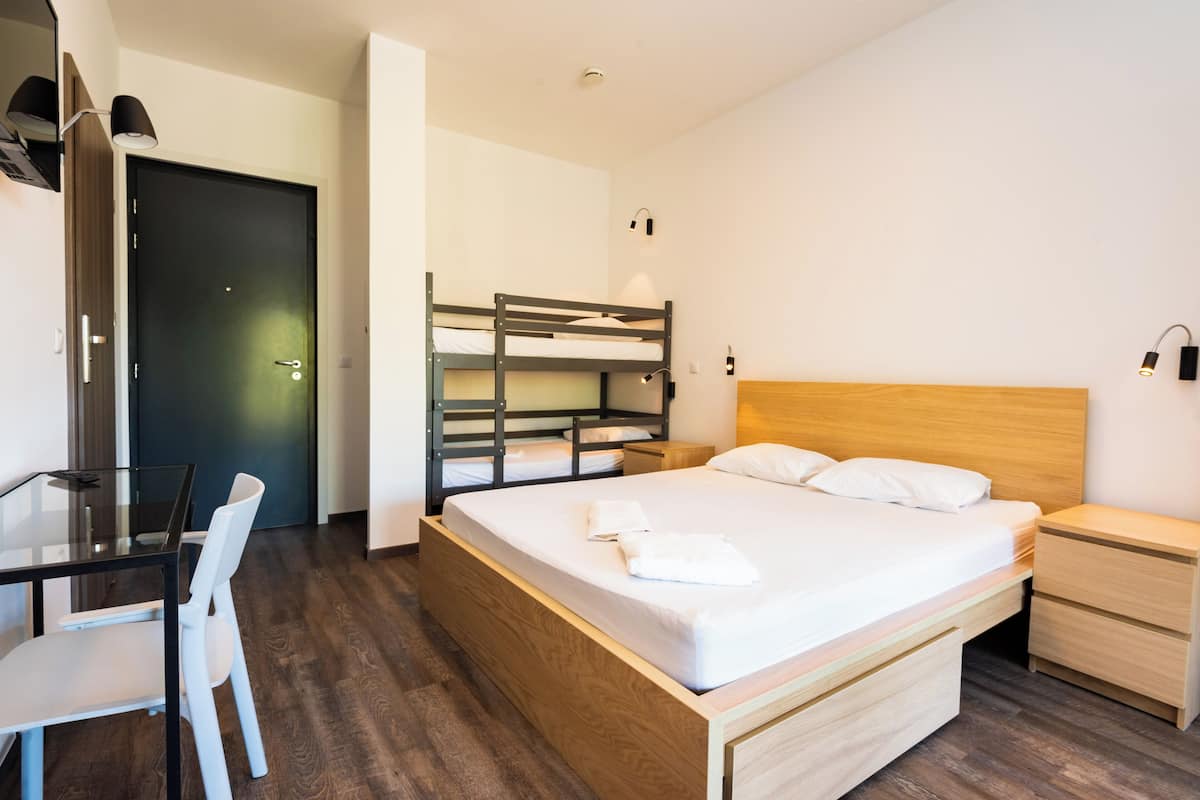 Ein Schlafzimmer mit Etagenbett, Nachttisch, Schreibtisch und Stuhl sowie einer Tür.