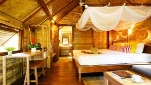 Quarto estilo cabana de madeira, com cama, escrivaninha e mosquiteiro suspenso.