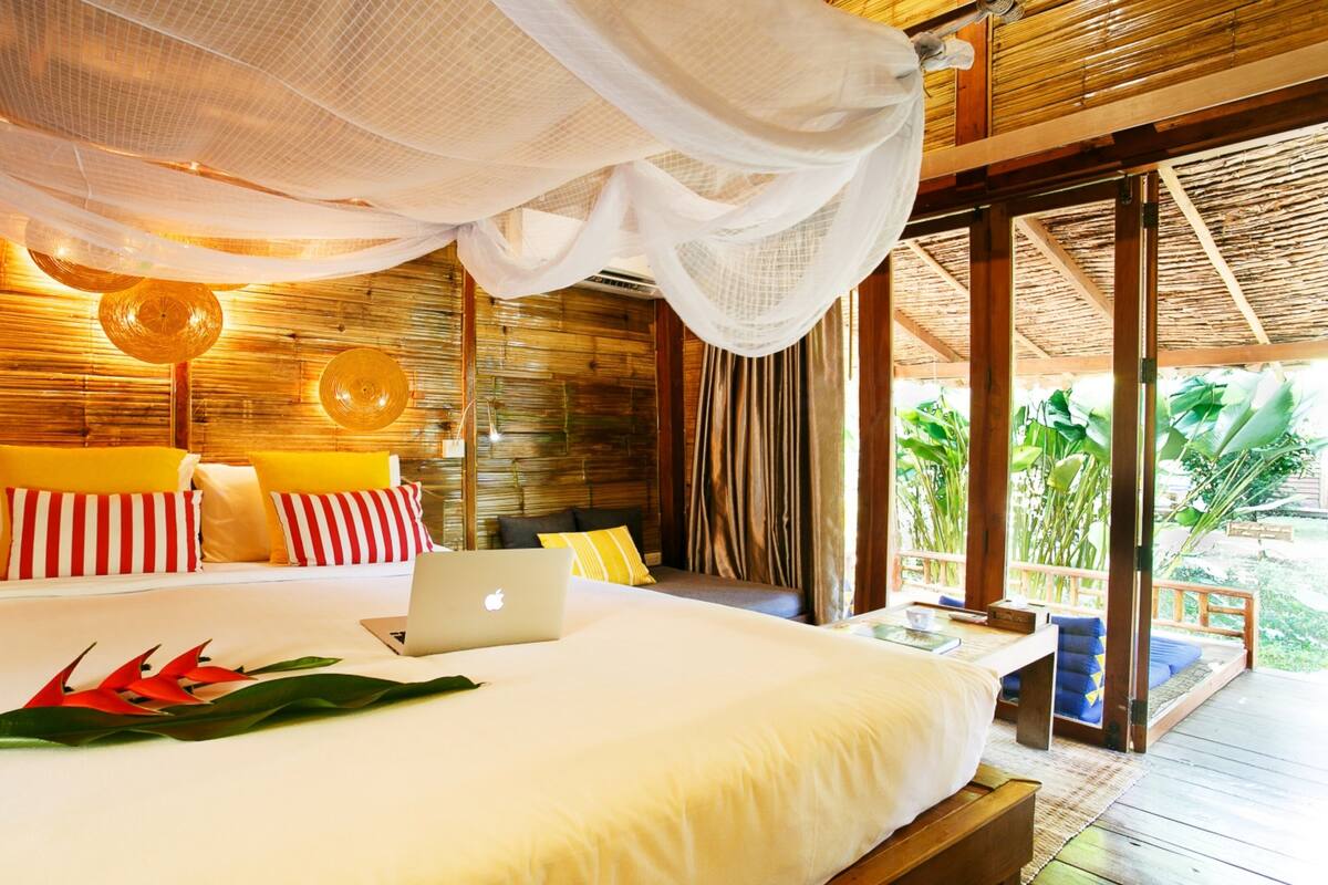 A spacious bedroom with a bed, a laptop, and a canopy.