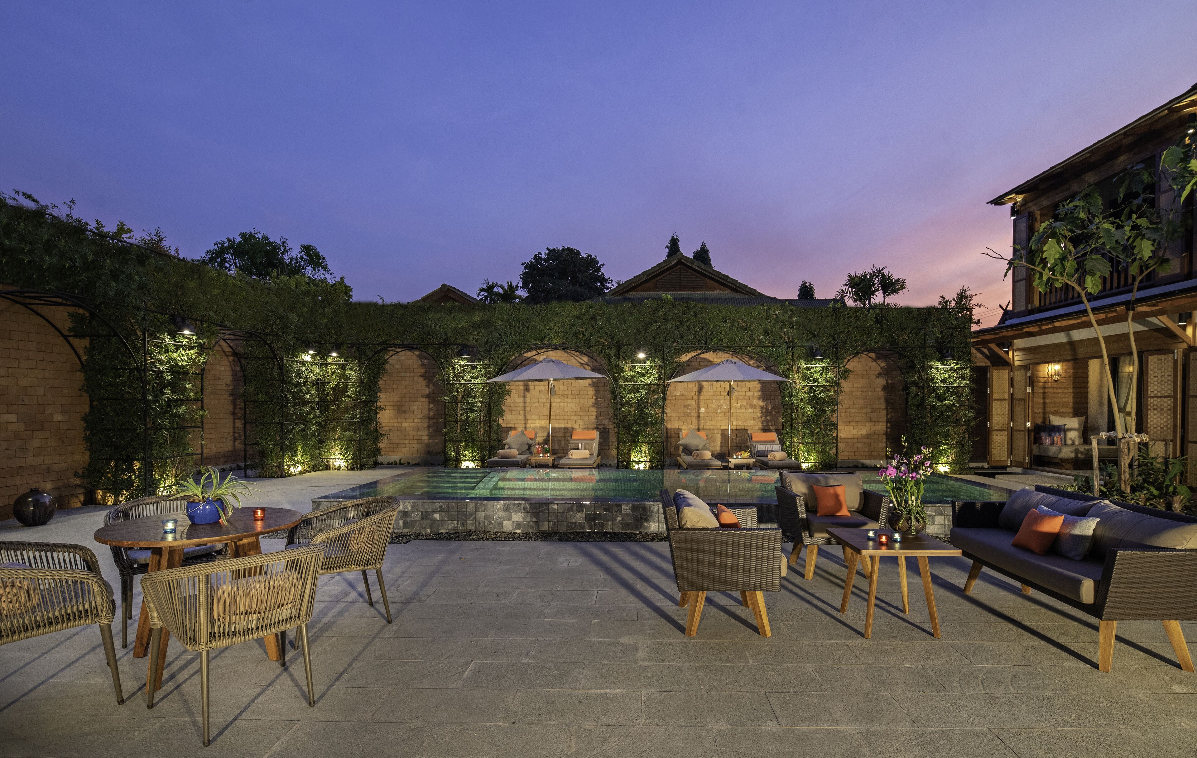 A courtyard with a pool, outdoor seating, and a traditional building.
