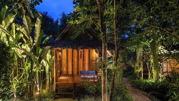 Eine Holzhütte mit Veranda, umgeben von dichtem Grün.