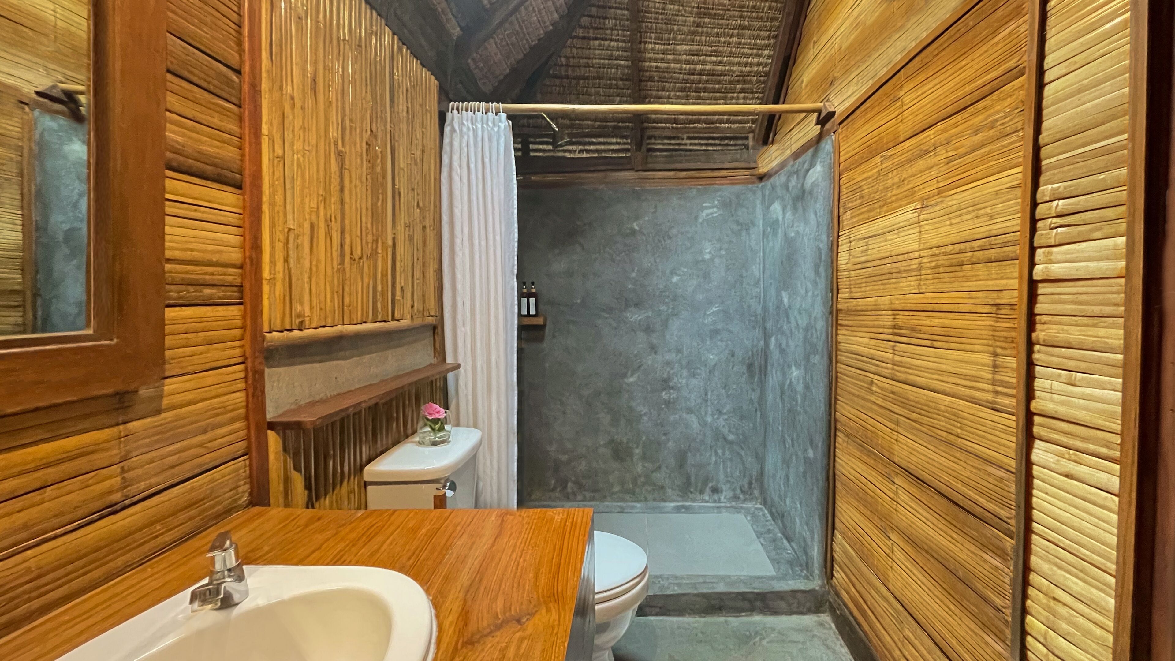 A compact bathroom with wooden walls, a white sink, and a toilet.