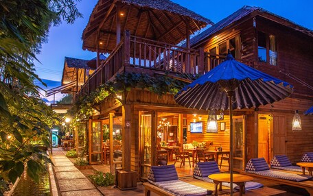 A wooden building with a balcony, outdoor seating, and a small pool.