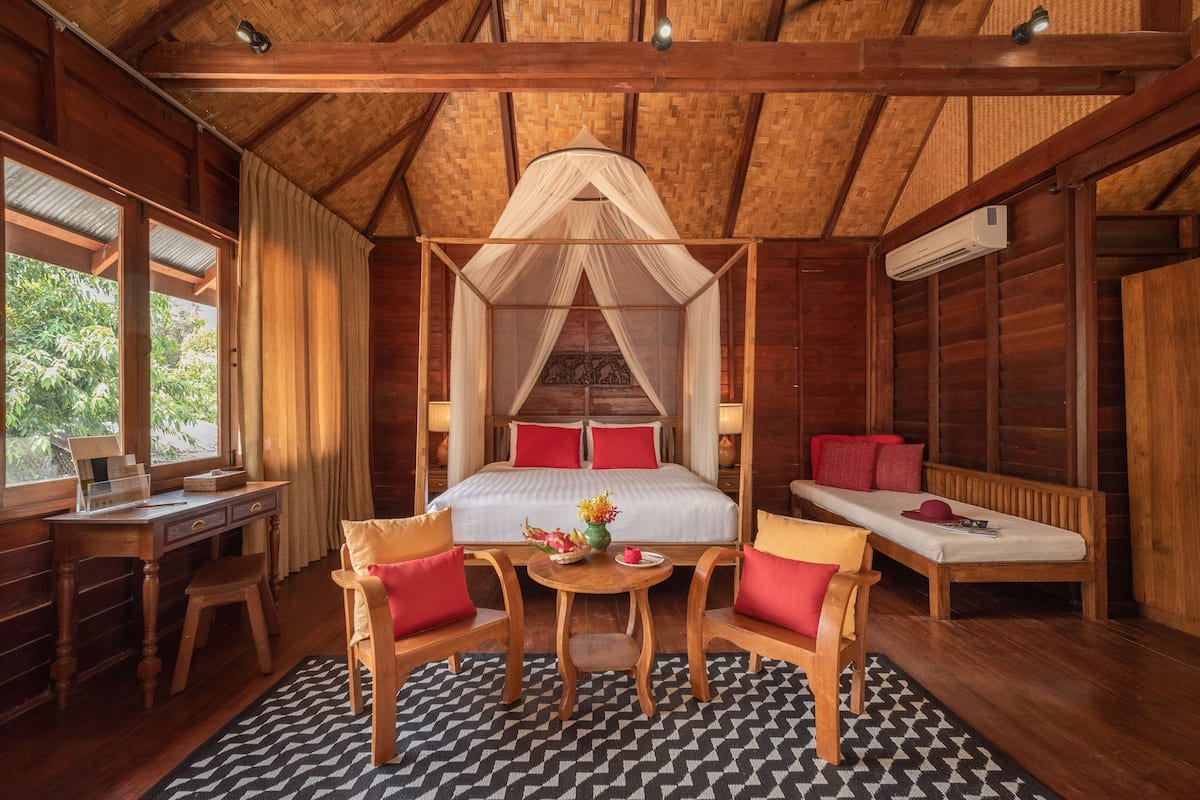 A wooden room with a bed, a desk, and two chairs.