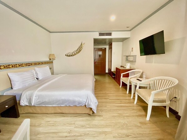 A hotel room with a bed, a desk, a chair, a television, and a decorative wall piece.